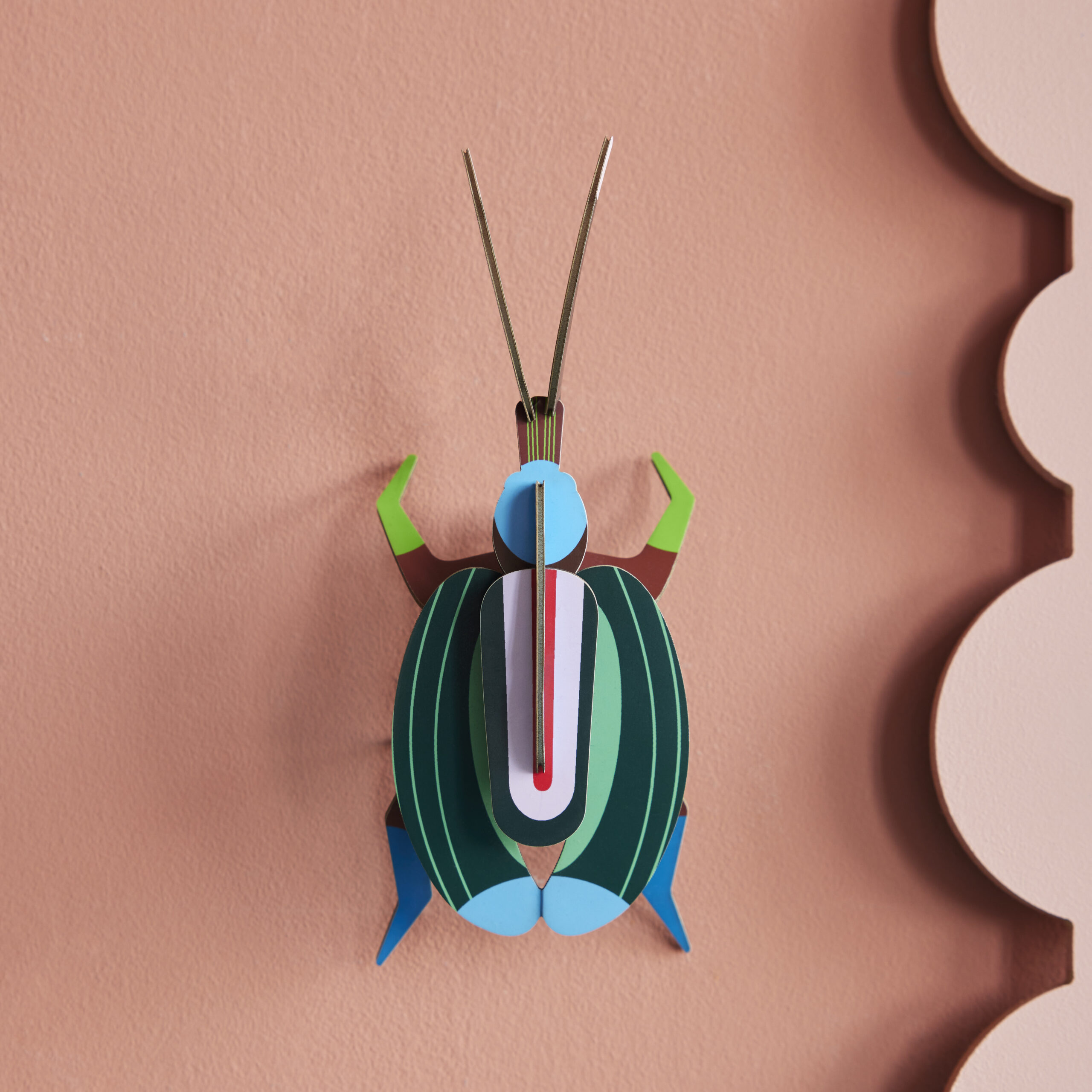 Green Fig Beetle - Grüner Feigenkaefer mit Streifen aus Papier in 3D als Wanddekoration von der Firma studio Roof auf rosa Wand