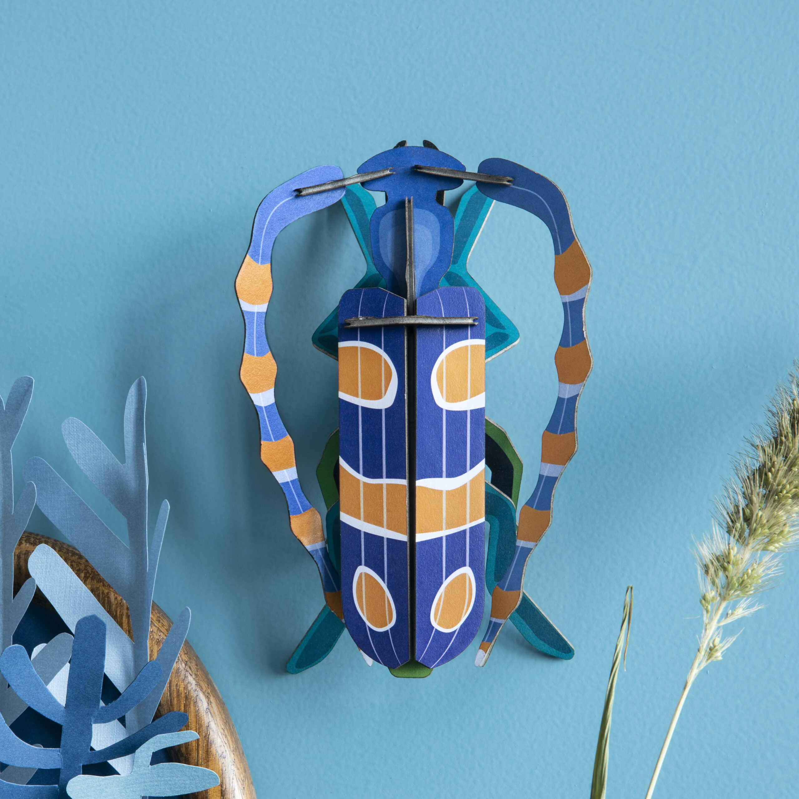 Rosalie Beetle - gemusterter Kaefer aus Papier in 3D als Wanddekoration von der Firma studio Roof an blauer Wand