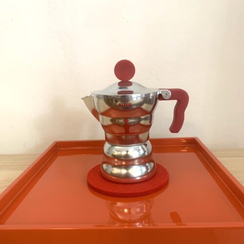 Espressokanne Moca von Alessi mit rotem Griff auf rotem Tablett